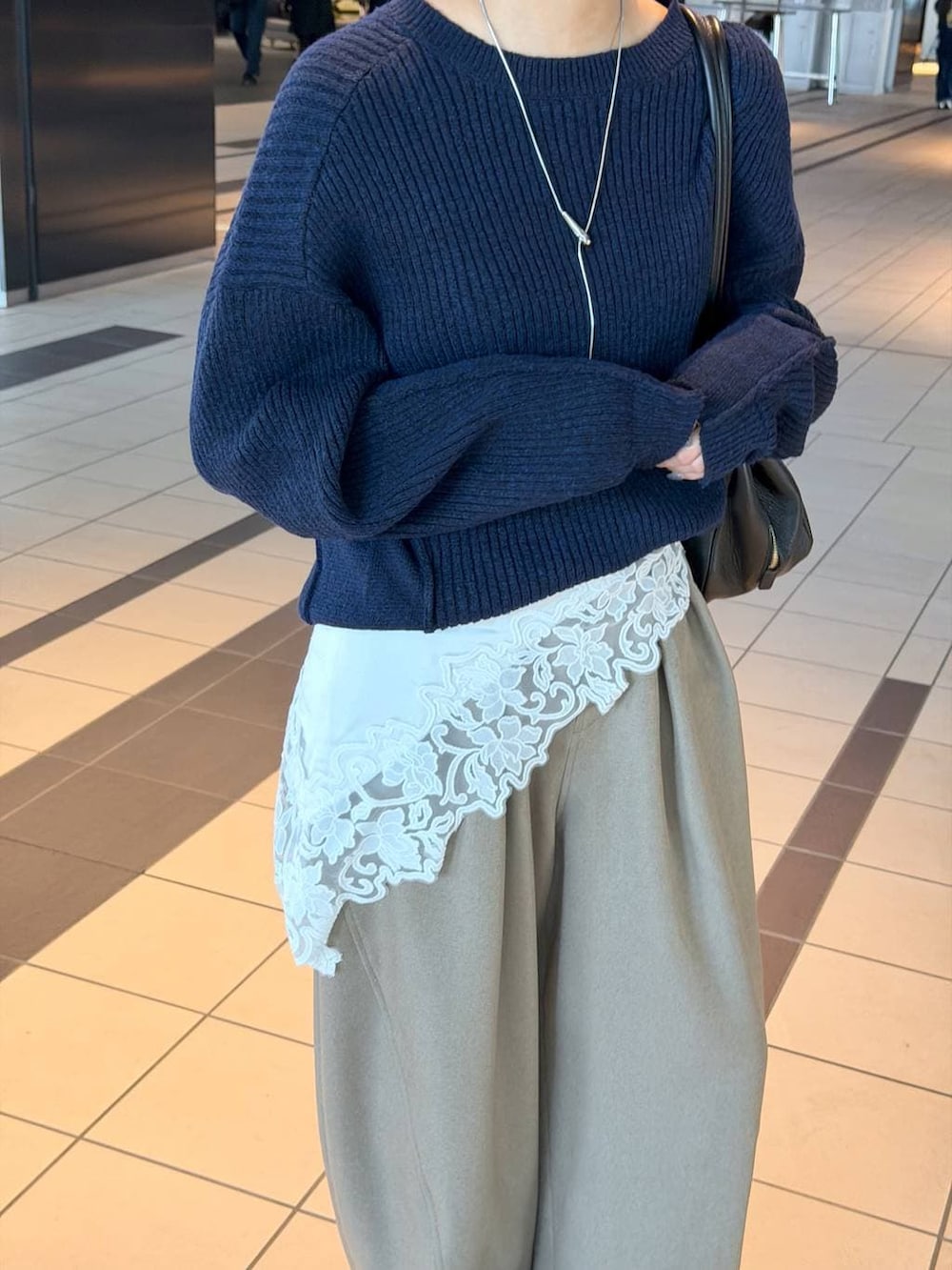 ブラック系のハンドバッグ、ブラック系のローファー、ブルー系のニット/セーターを着用したレディースの冬コーディネートの4枚目の写真