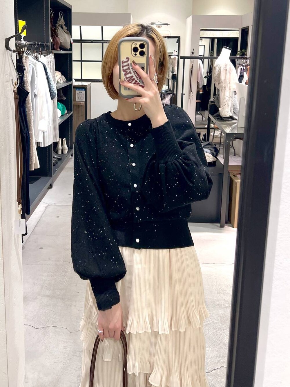 ブラック系のブーツ、ホワイト系のスカート、ブラック系のカーディガン/ボレロを着用したレディースの秋コーディネートの2枚目の写真