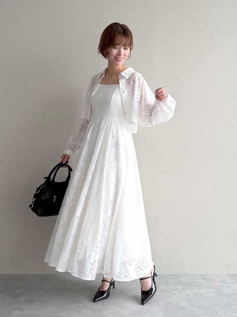 ブラック系のボストンバッグ、ブラック系のサンダル、ホワイト系のワンピースを着用したレディースの春コーディネートの4枚目の写真