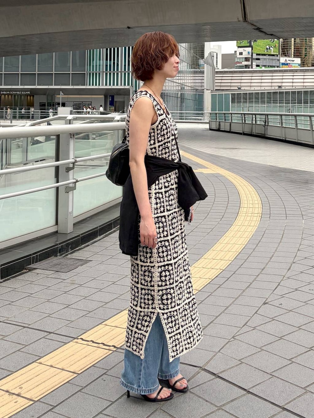 その他のワンピース、ブラック系のハンドバッグ、ブルー系のデニムパンツを着用したレディースの夏コーディネートの2枚目の写真