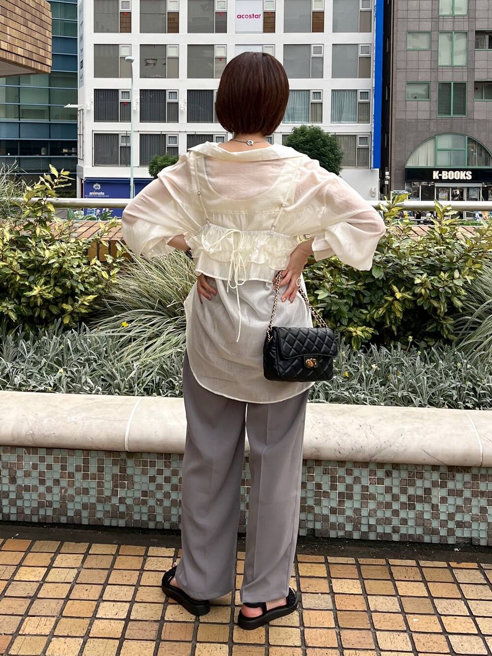 ブラック系のサンダル、グレー系のスラックス、ホワイト系のタンクトップを着用したレディースの夏コーディネートの2枚目の写真