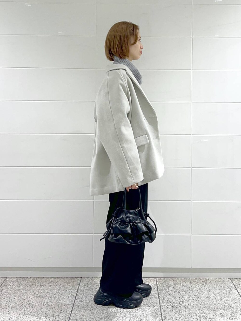 ブラック系のブーツ、ブラック系のショルダーバッグ、ホワイト系のその他アウターを着用したレディースの秋コーディネートの2枚目の写真