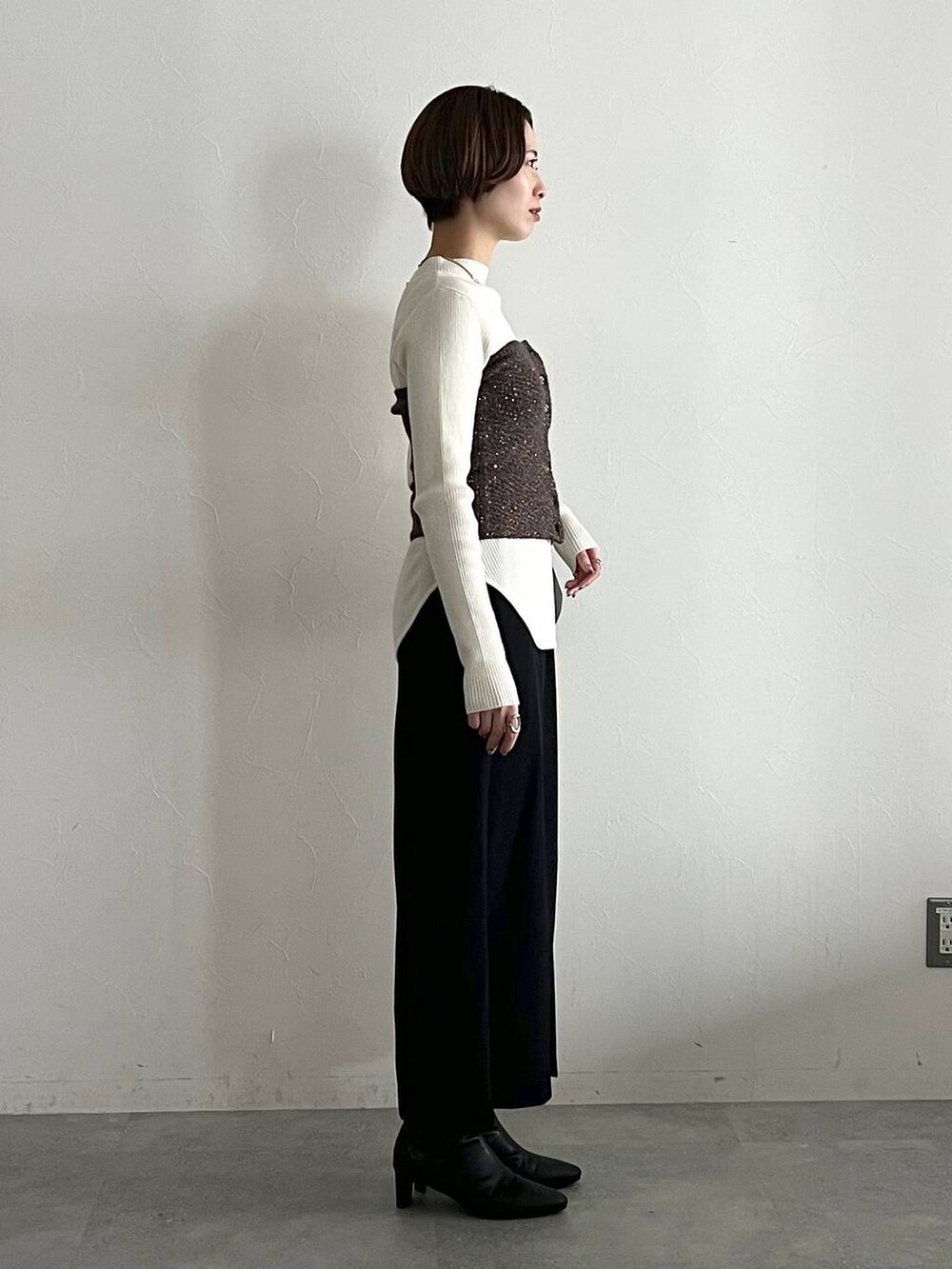 ホワイト系のニット/セーター、ブラック系のブーツ、ブラック系のスカートを着用したレディースの冬コーディネートの2枚目の写真