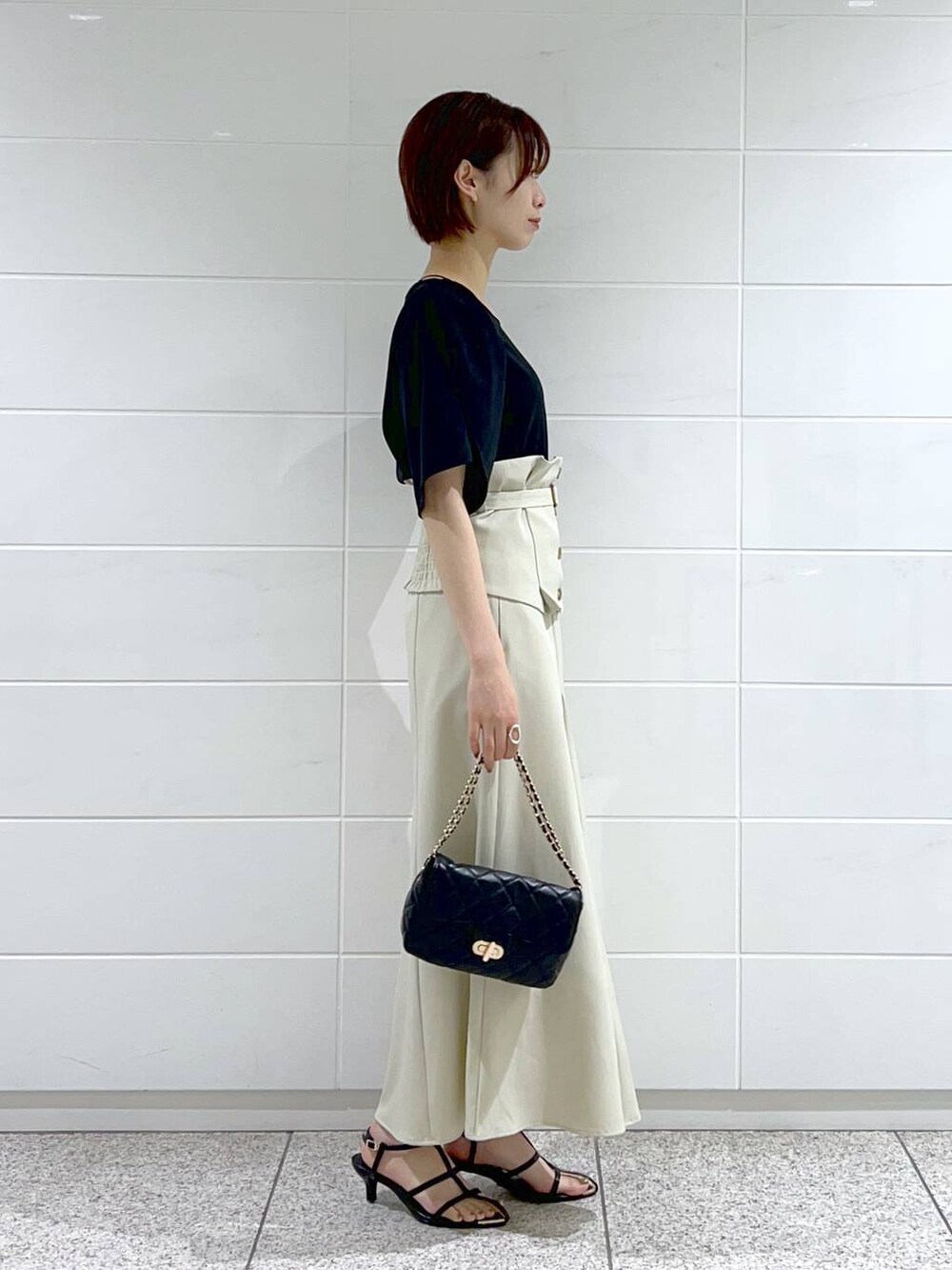 ホワイト系のスカート、ブラック系のショルダーバッグ、ブラック系のサンダルを着用したレディースの夏コーディネートの3枚目の写真