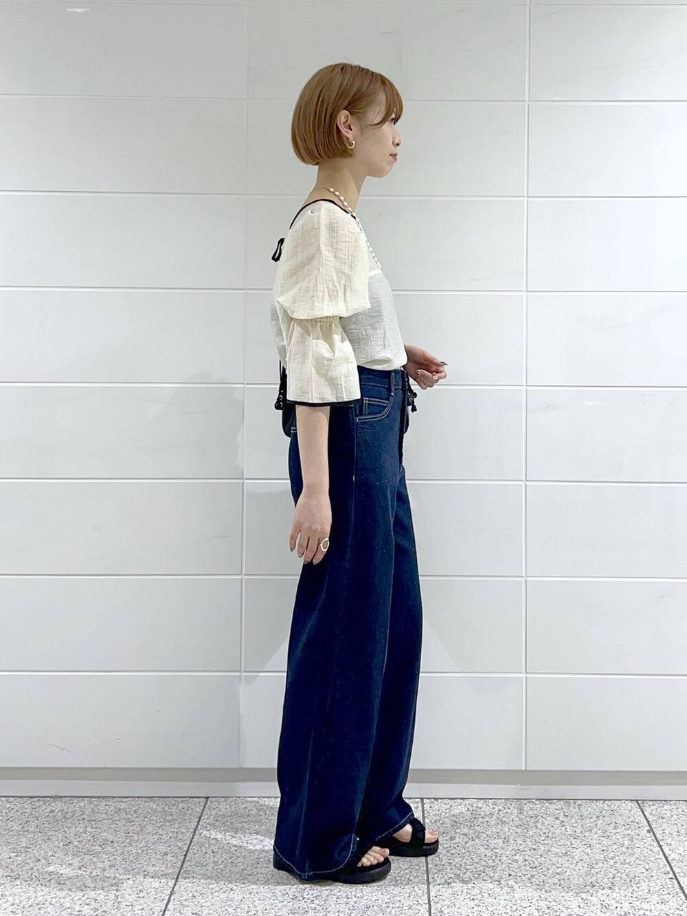 ブラック系のサンダル、ブルー系のデニムパンツ、ホワイト系のシャツ/ブラウスを着用したレディースの春コーディネートの2枚目の写真