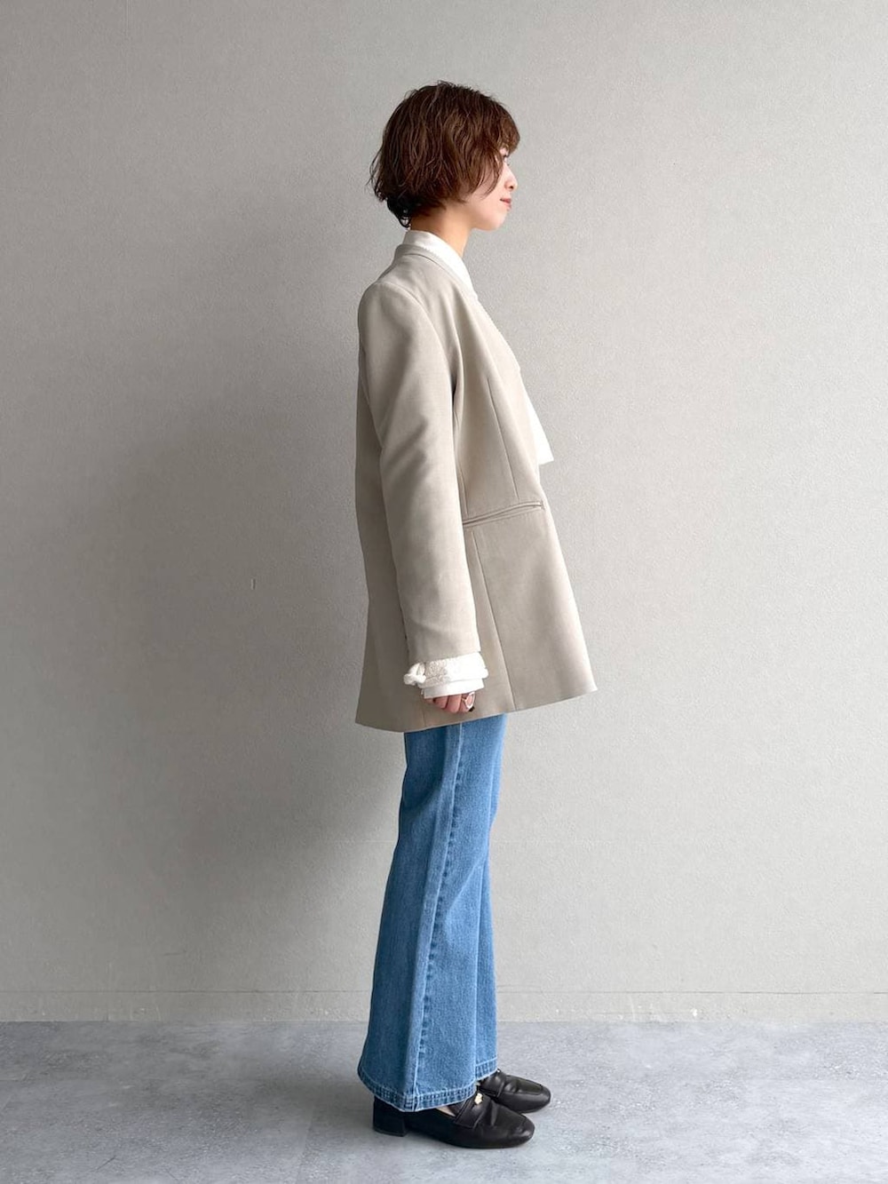 ブラック系のローファー、ブルー系のデニムパンツ、ベージュ系のテーラードジャケットを着用したレディースの冬コーディネートの2枚目の写真