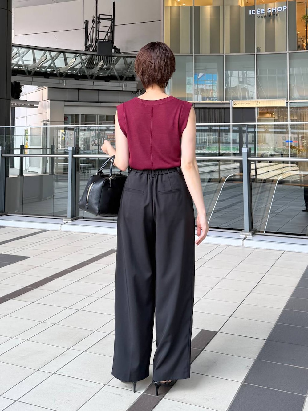 レッド系のニット/セーター、ブラック系のその他パンツ、ブラック系のハンドバッグを着用したレディースの夏コーディネートの3枚目の写真