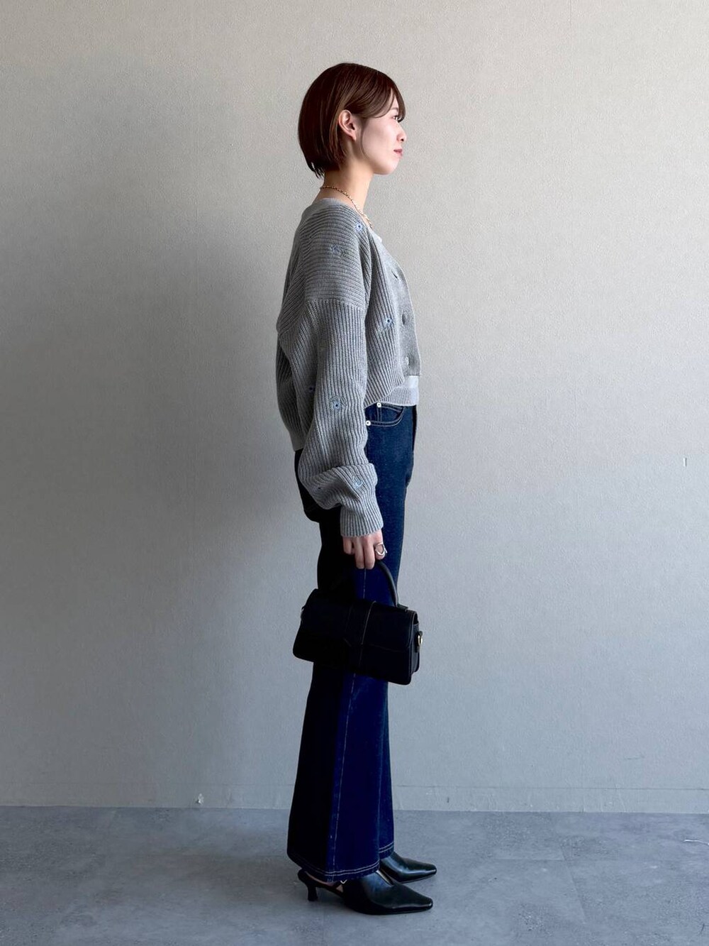 ブラック系のショルダーバッグ、ブルー系のデニムパンツ、ブラック系のサンダルを着用したレディースの冬コーディネートの2枚目の写真