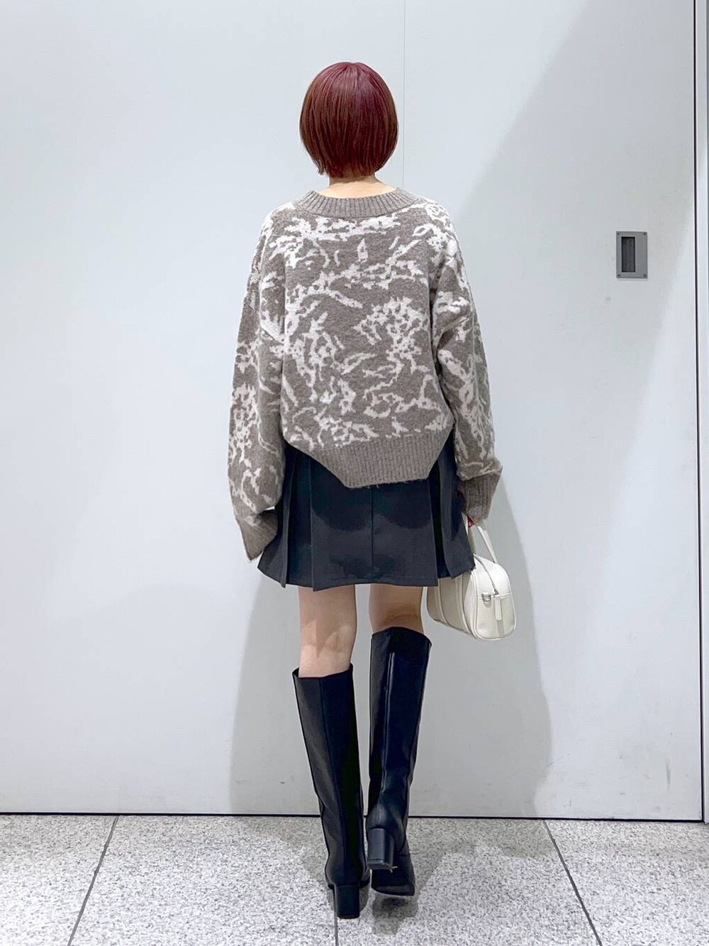 ブラック系のブルゾン、ホワイト系のボストンバッグ、ブラック系のブーツを着用したレディースの秋コーディネートの6枚目の写真