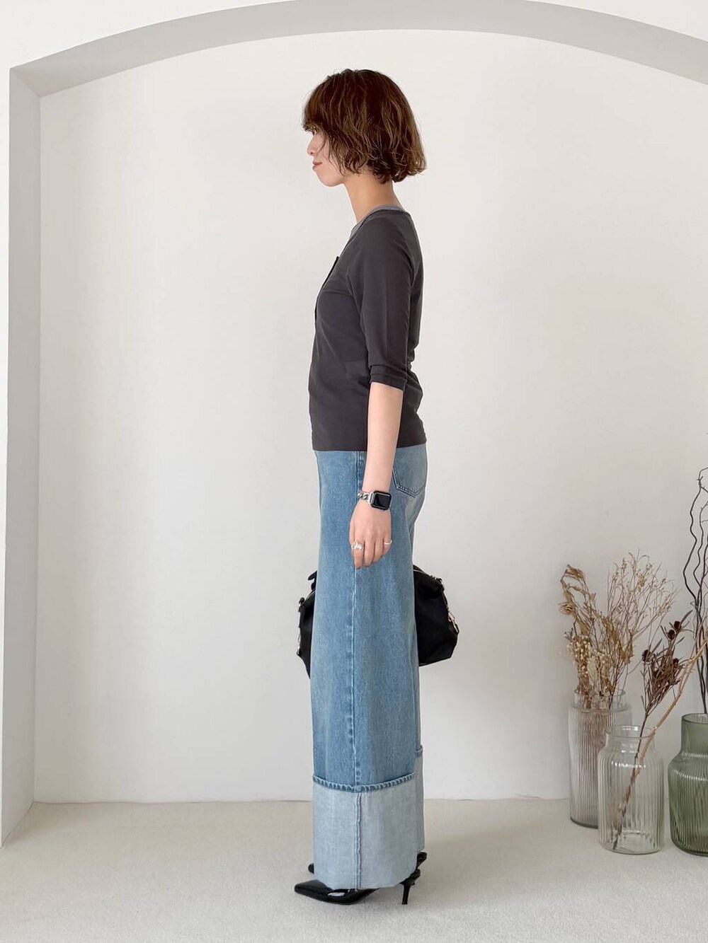 ブラック系のボストンバッグ、ブラック系のサンダル、ブルー系のデニムパンツを着用したレディースの春コーディネートの2枚目の写真