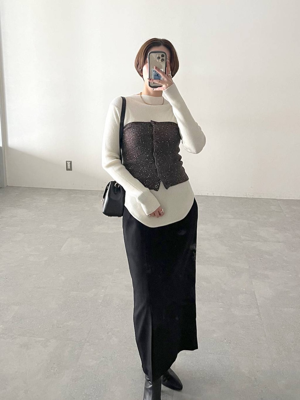 ホワイト系のニット/セーター、ブラック系のブーツ、ブラック系のスカートを着用したレディースの冬コーディネートの4枚目の写真