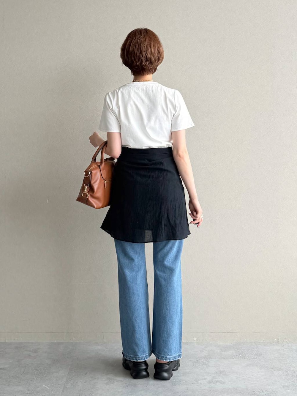 ブラウン系のボストンバッグ、ブルー系のデニムパンツ、ブラック系のシャツ/ブラウスを着用したレディースの夏コーディネートの3枚目の写真