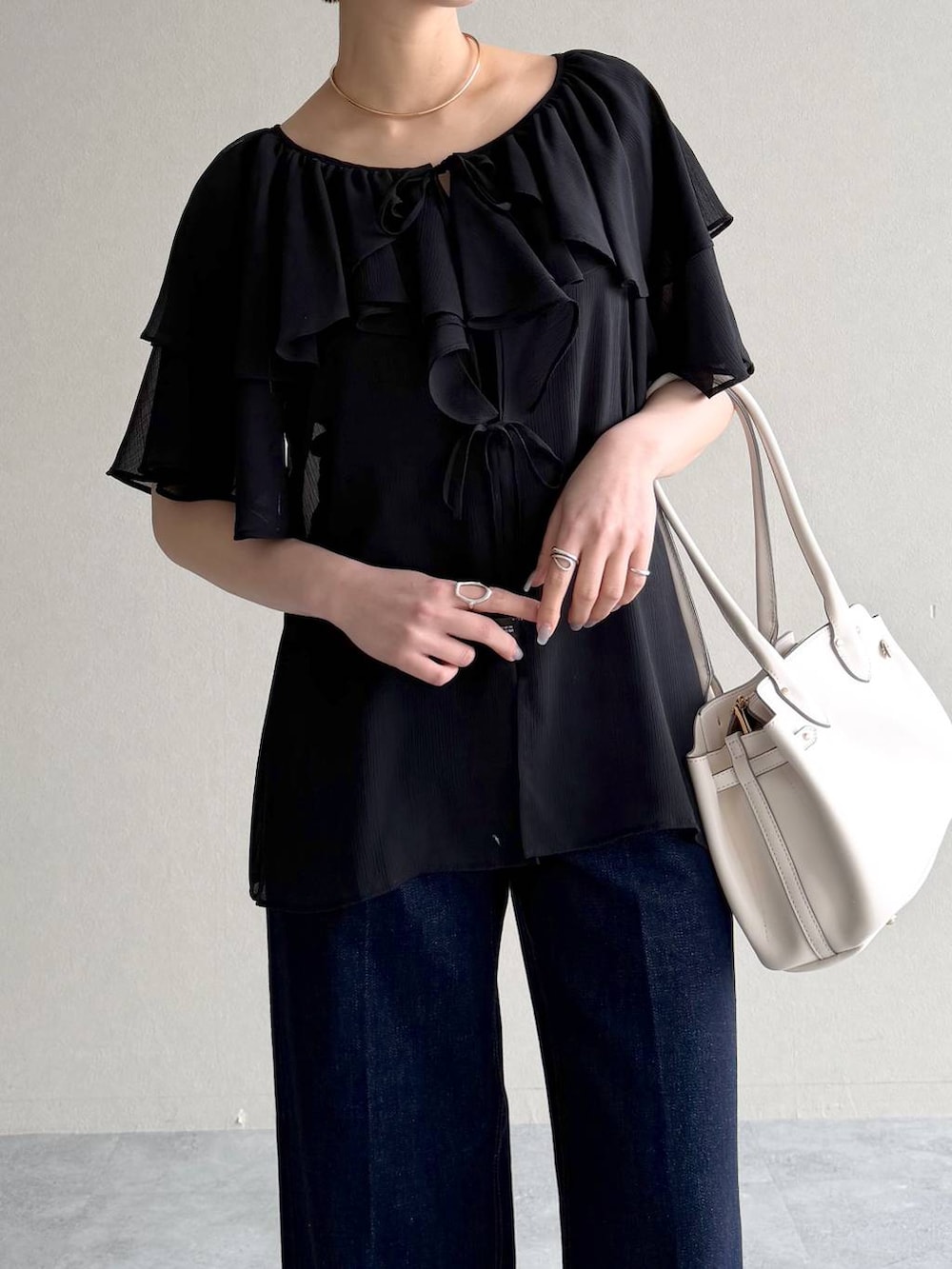 ホワイト系のサンダル、ブルー系のデニムパンツ、ブラック系のシャツ/ブラウスを着用したレディースの春コーディネートの4枚目の写真