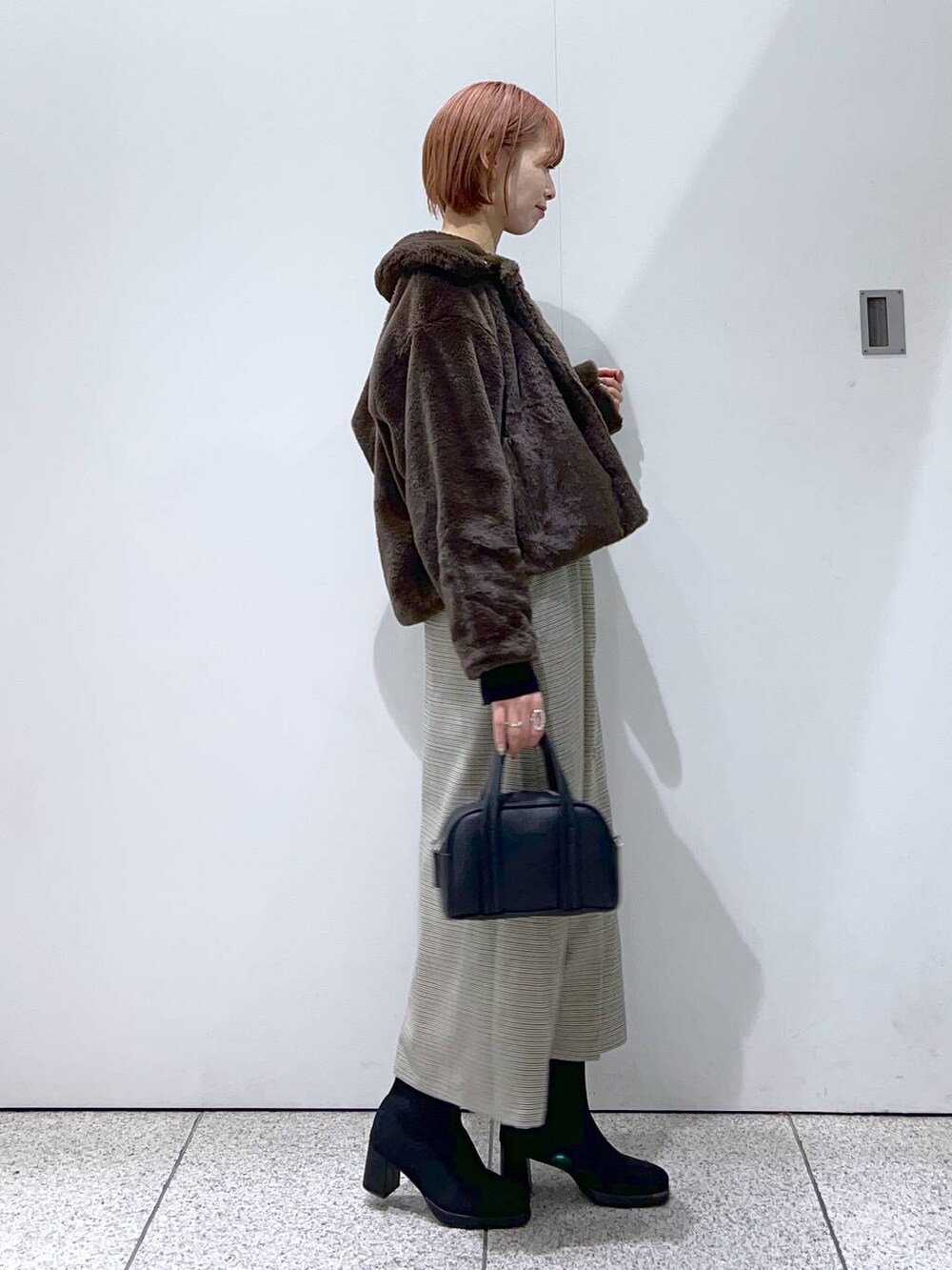 ブラック系のボストンバッグ、ブラック系のブーツ、ブラック系のニット/セーターを着用したレディースの冬コーディネートの2枚目の写真