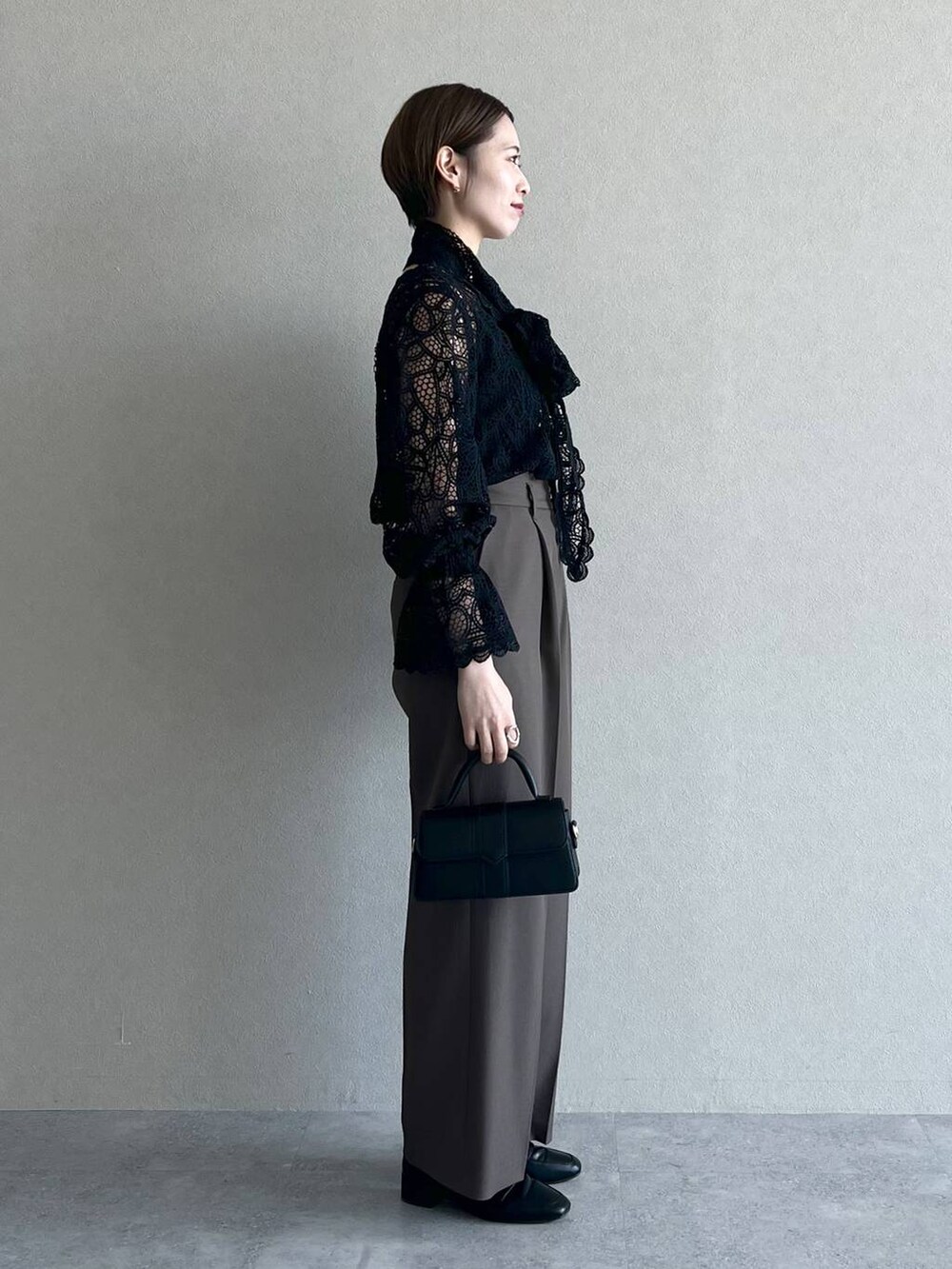 ブラック系のシャツ/ブラウス、ブラウン系のスラックス、ブラック系のローファーを着用したレディースの秋コーディネートの2枚目の写真