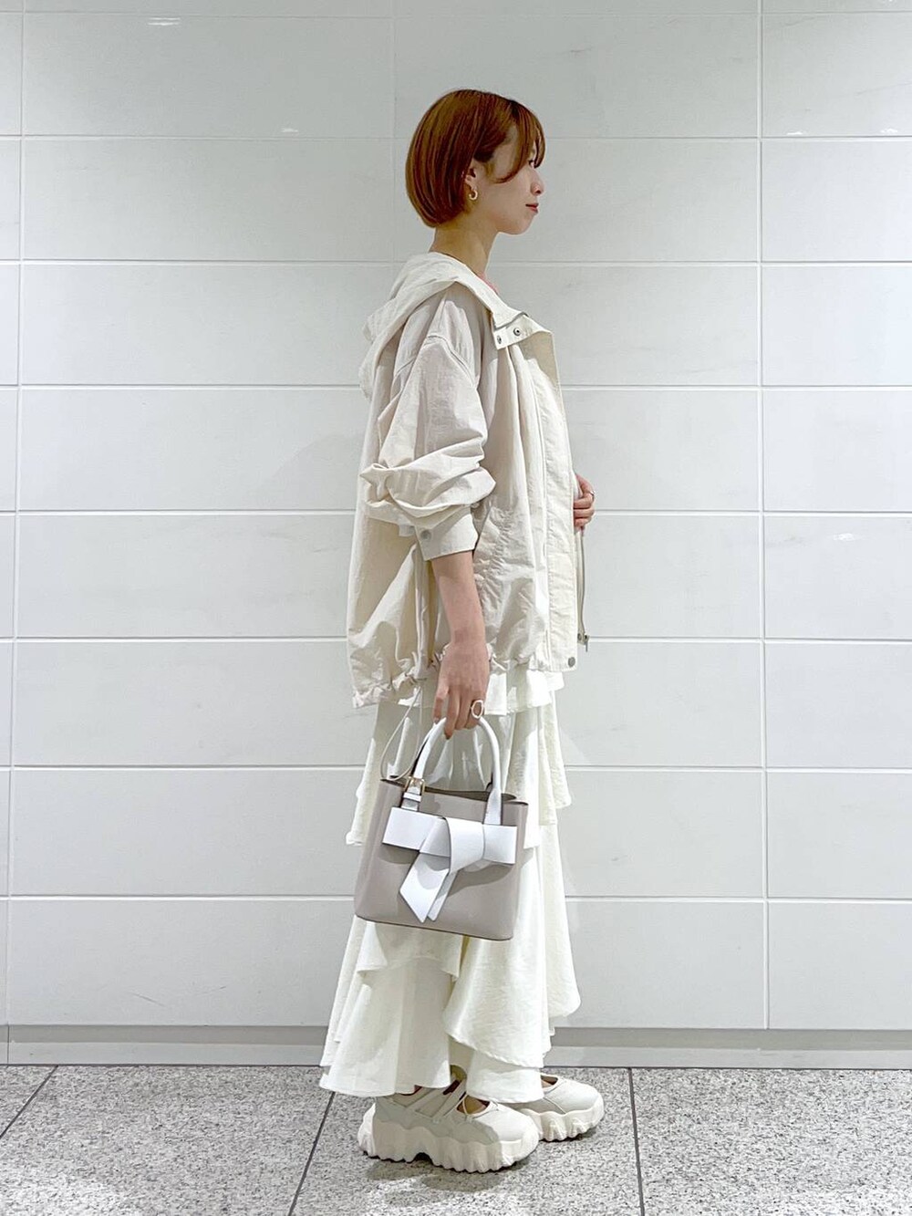 ホワイト系のスカート、ベージュ系のショルダーバッグ、ホワイト系のマウンテンパーカーを着用したレディースの春コーディネートの2枚目の写真