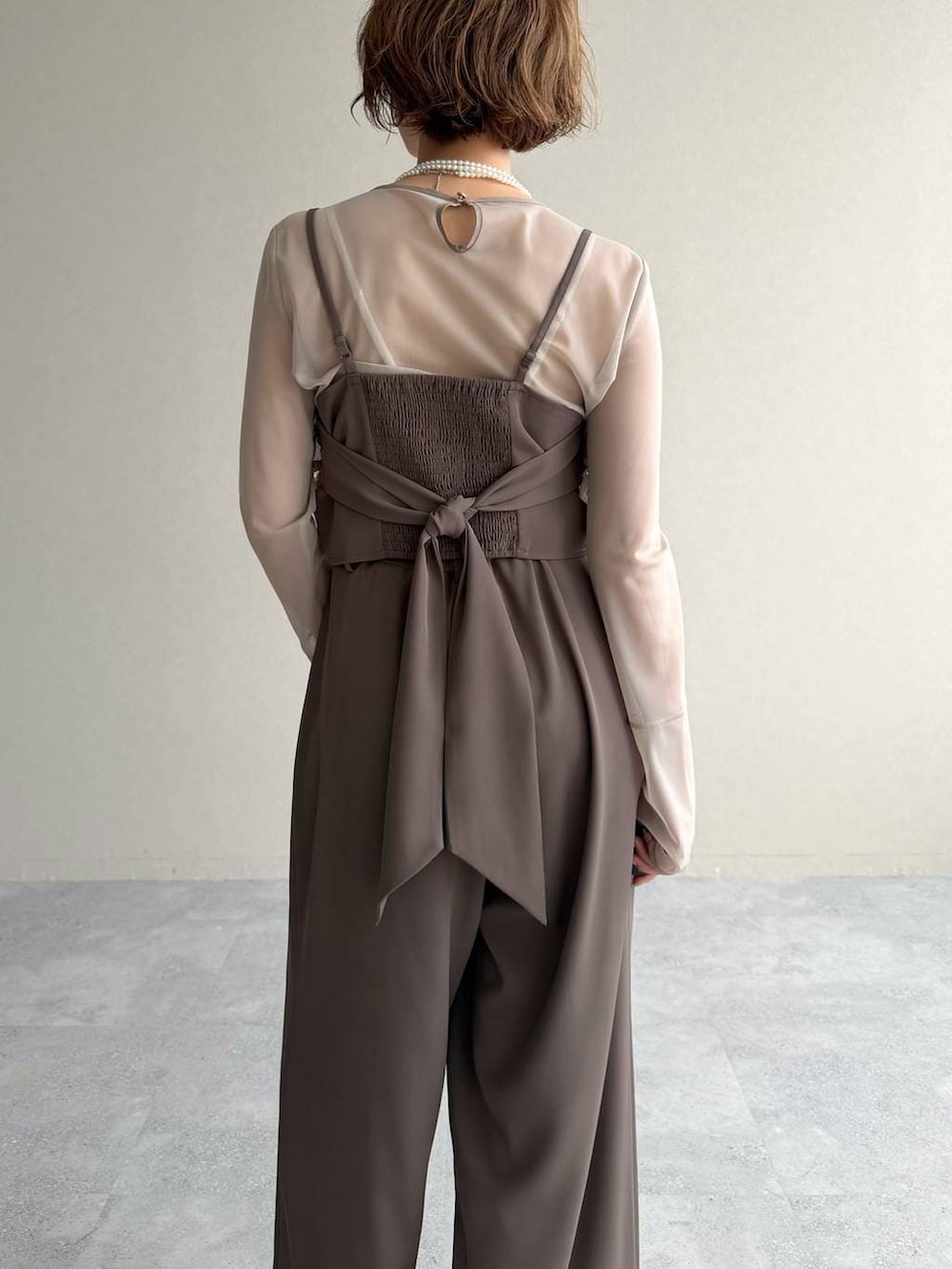 ブラック系のパンプス、ホワイト系のショルダーバッグ、ベージュ系のパンツドレスを着用したレディースの春コーディネートの6枚目の写真