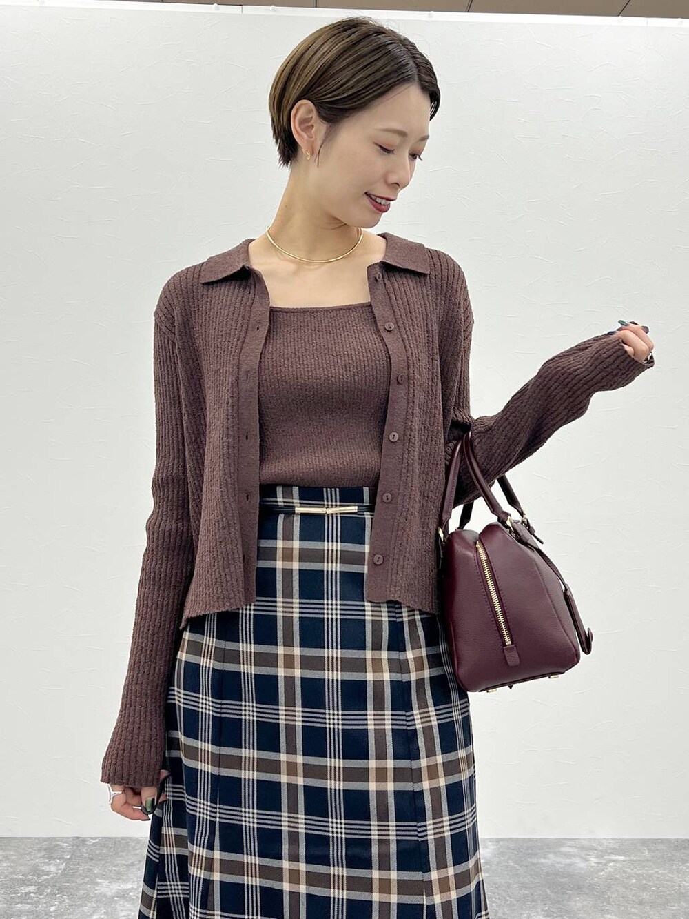 レッド系のハンドバッグ、ブラウン系のカーディガン/ボレロ、ブラウン系のニット/セーターを着用したレディースの秋コーディネートの4枚目の写真