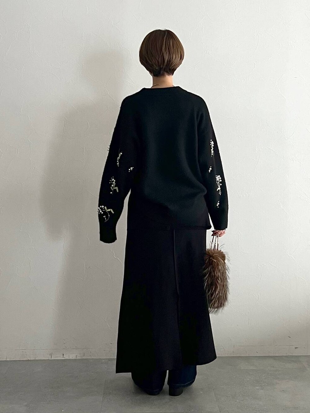 ブラック系のニット/セーター、ブルー系のデニムパンツ、ブラック系のローファーを着用したレディースの秋コーディネートの3枚目の写真