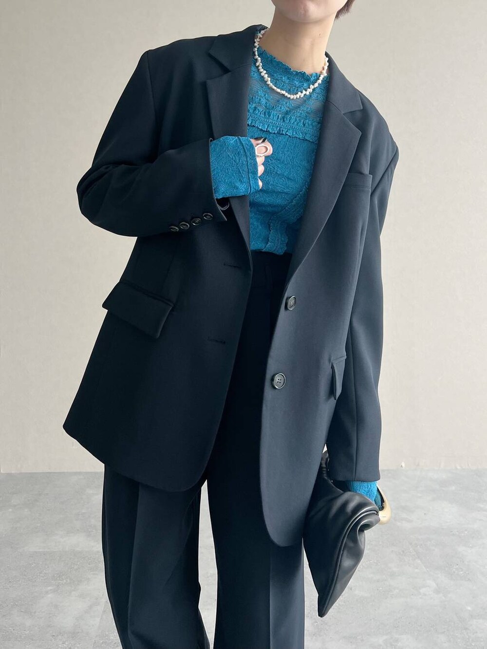 ブラック系のハンドバッグ、ブルー系のTシャツ/カットソー、ブルー系のスラックスを着用したレディースの秋コーディネートの5枚目の写真