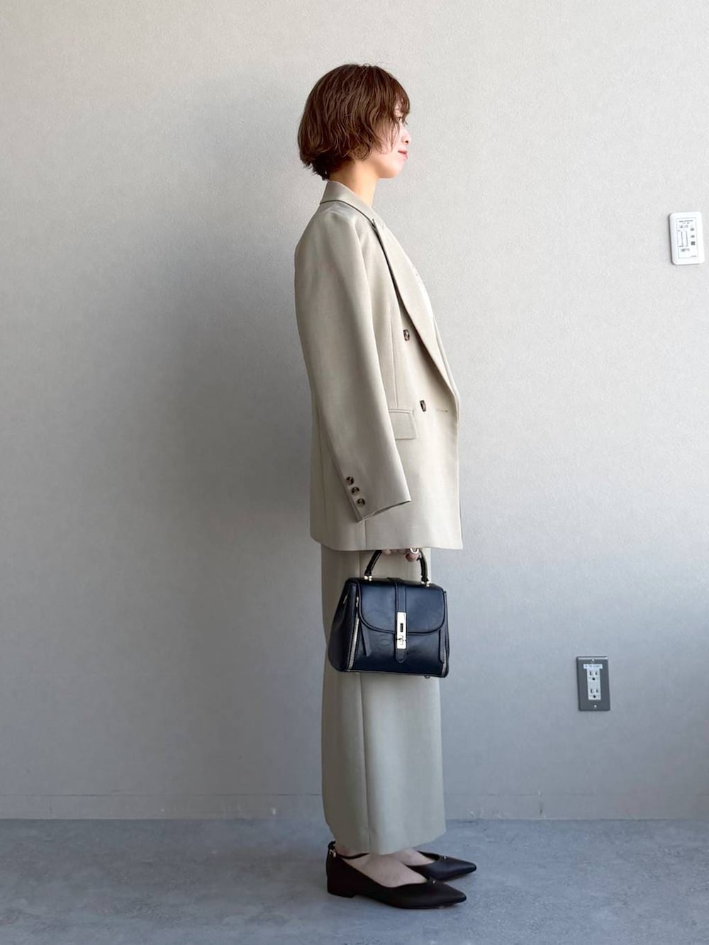 ブラック系のショルダーバッグ、ベージュ系のテーラードジャケット、ベージュ系のスカートを着用したレディースの冬コーディネートの2枚目の写真