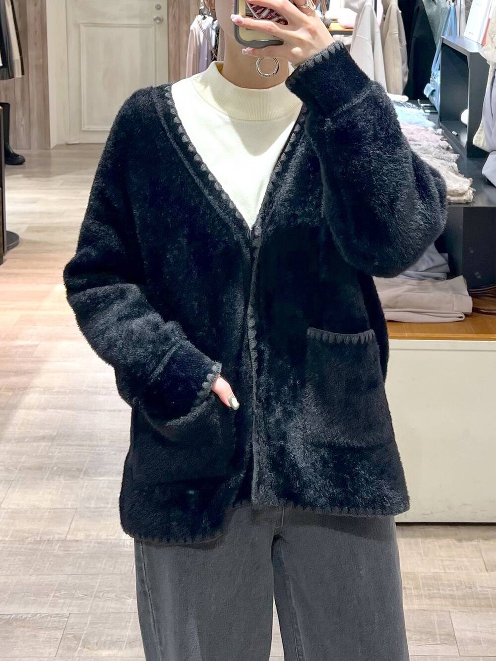 ブラック系のデニムパンツ、ブラック系のブーツ、ブラウン系のハンドバッグを着用したレディースの秋コーディネートの7枚目の写真