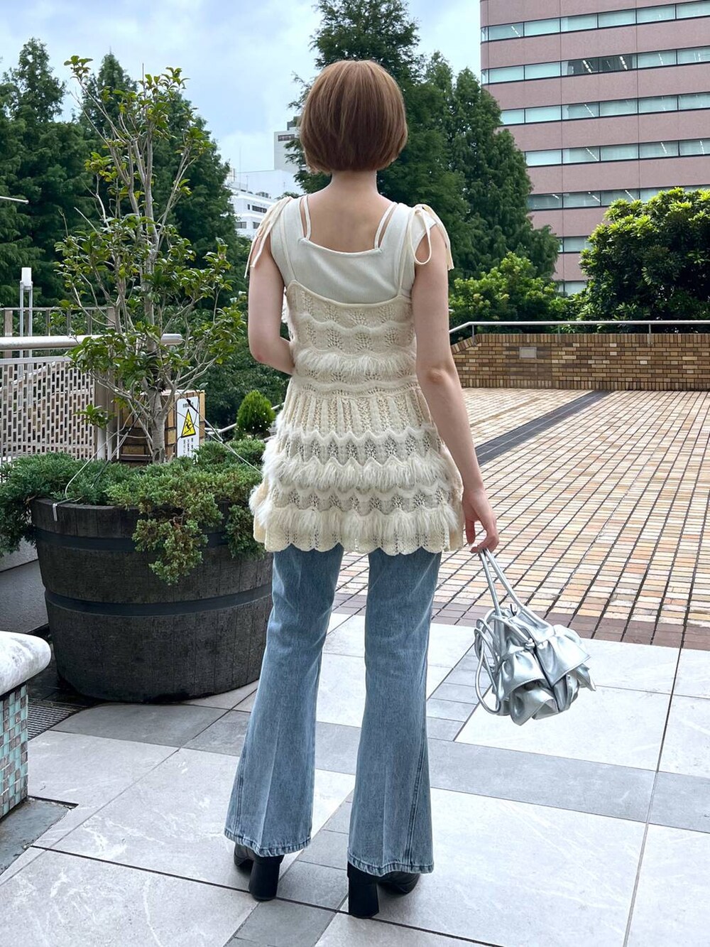 ブルー系のデニムパンツ、ホワイト系のキャミソール、ホワイト系のニット/セーターを着用したレディースの秋コーディネートの3枚目の写真