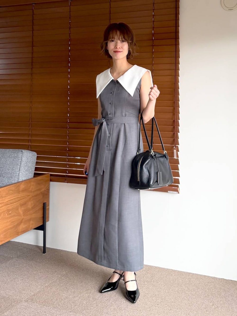ブラック系のハンドバッグ、ブラック系のサンダル、グレー系のワンピースを着用したレディースの春コーディネートの5枚目の写真