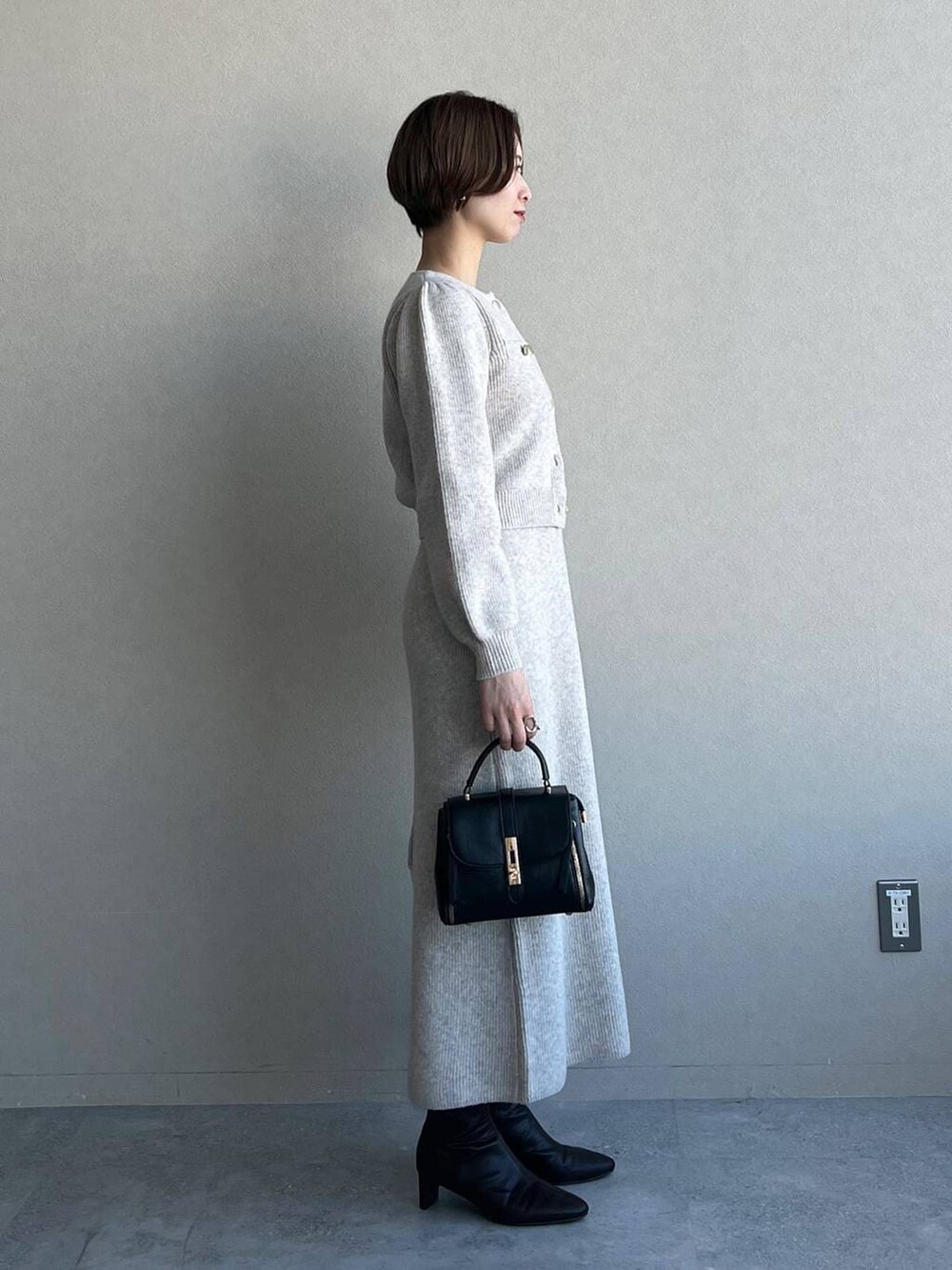 ブラック系のブーツ、ブラック系のショルダーバッグ、ホワイト系のワンピースを着用したレディースの冬コーディネートの2枚目の写真