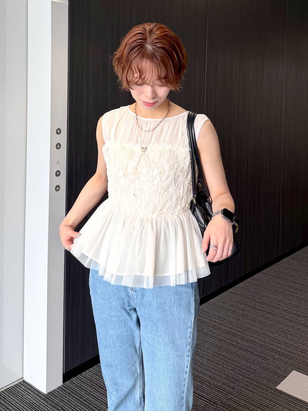 ブラック系のハンドバッグ、ブルー系のデニムパンツを着用したレディースの夏コーディネートの4枚目の写真