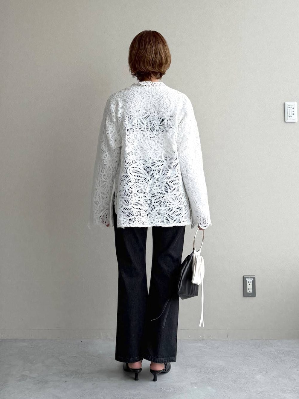 ブラック系のデニムパンツ、ブラック系のサンダル、ブラウン系のブルゾンを着用したレディースの冬コーディネートの7枚目の写真