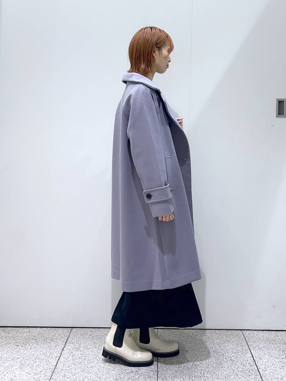 グレー系のチェスターコート、ホワイト系のブーツ、ホワイト系のニット/セーターを着用したレディースの秋コーディネートの2枚目の写真