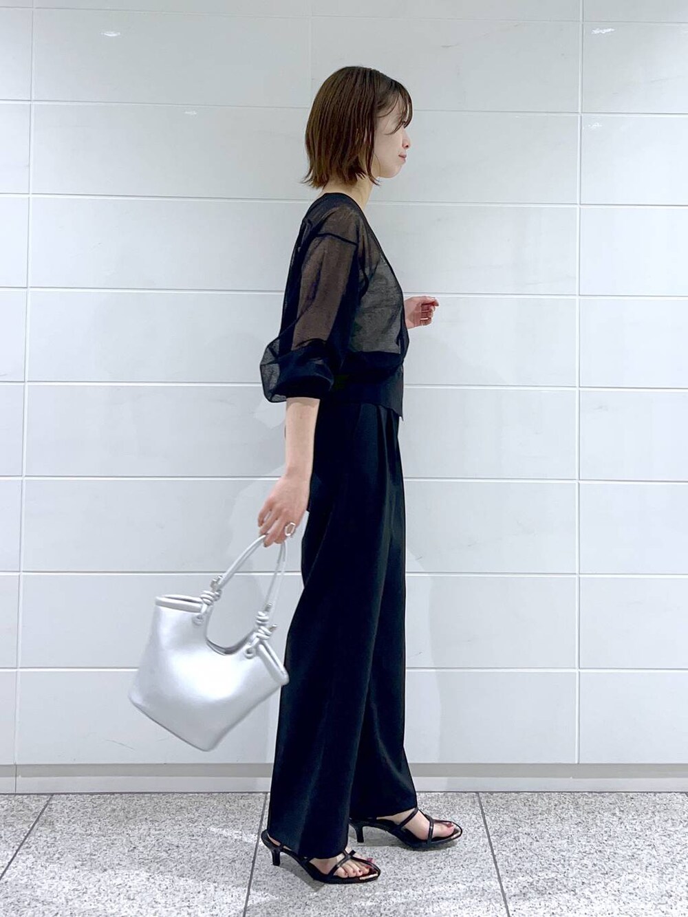 ホワイト系のキャミソール、ブラック系のサンダル、シルバー系のハンドバッグを着用したレディースの春コーディネートの2枚目の写真