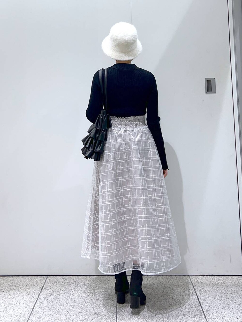 ブラウン系のチェスターコート、ブラック系のブーツ、ブラック系のニット/セーターを着用したレディースの冬コーディネートの6枚目の写真