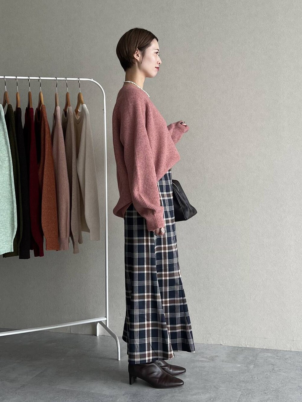 ピンク系のニット/セーター、ブラウン系のブーツ、ブラウン系のトートバッグを着用したレディースの秋コーディネートの2枚目の写真