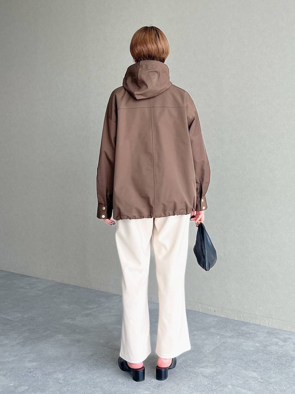 ブラック系のハンドバッグ、ブラウン系のマウンテンパーカー、ブラック系のスリッポンを着用したレディースの秋コーディネートの4枚目の写真