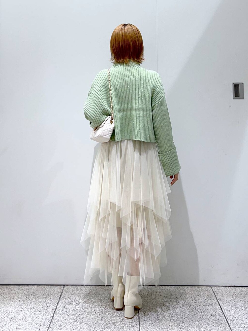 ホワイト系のショルダーバッグ、ホワイト系のブーツ、ホワイト系のスカートを着用したレディースの冬コーディネートの3枚目の写真