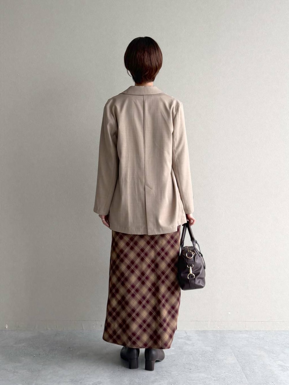 レッド系のスカート、ホワイト系のTシャツ/カットソー、ベージュ系のテーラードジャケットを着用したレディースの秋コーディネートの3枚目の写真