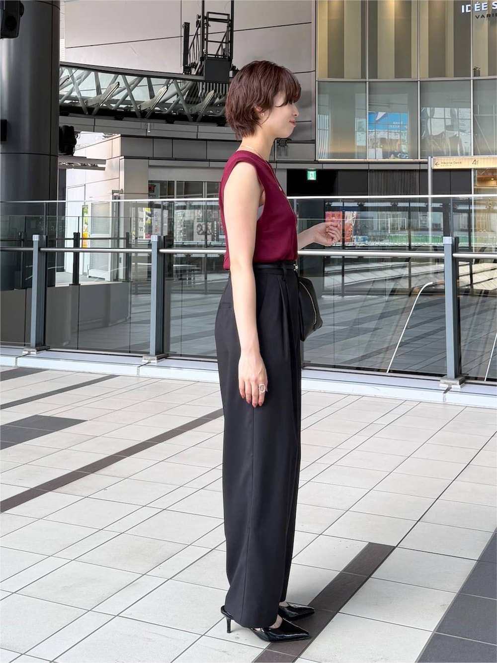 レッド系のニット/セーター、ブラック系のその他パンツ、ブラック系のハンドバッグを着用したレディースの夏コーディネートの2枚目の写真