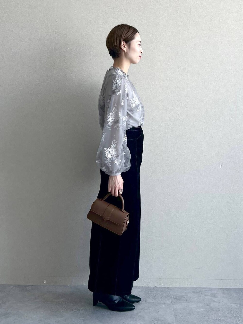 グレー系のシャツ/ブラウス、ブラック系のスカート、ブラック系のブーツを着用したレディースの秋コーディネートの2枚目の写真