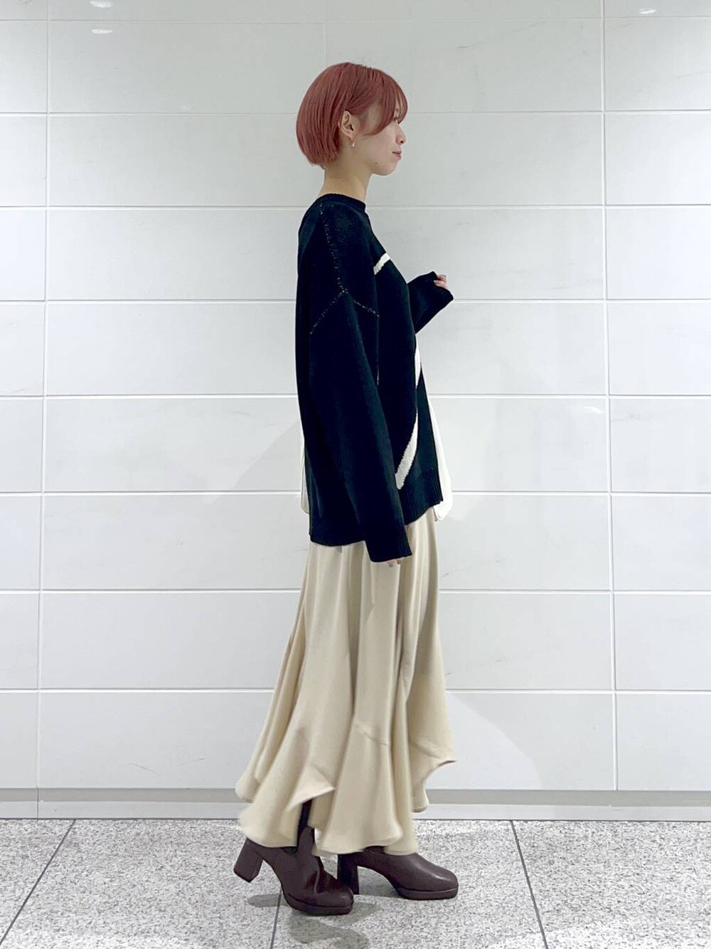 ホワイト系のトートバッグ、ブラウン系のブーツ、ベージュ系のスカートを着用したレディースの冬コーディネートの2枚目の写真