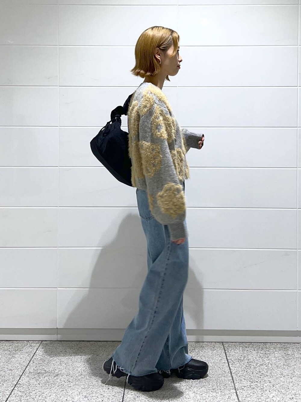 ブルー系のデニムパンツ、ブラック系のブーツ、ブラック系のショルダーバッグを着用したレディースの秋コーディネートの2枚目の写真