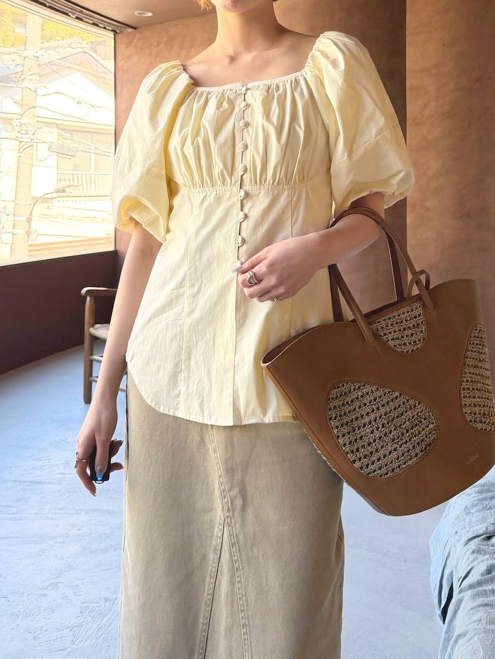 ブラウン系のトートバッグ、ブラウン系のサンダル、ホワイト系のシャツ/ブラウスを着用したレディースの春コーディネートの4枚目の写真