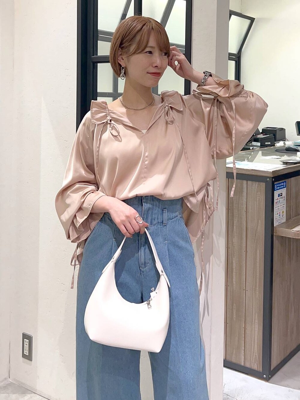 ブラウン系のパンプス、ブルー系のデニムパンツ、ホワイト系のショルダーバッグを着用したレディースの春コーディネートの3枚目の写真