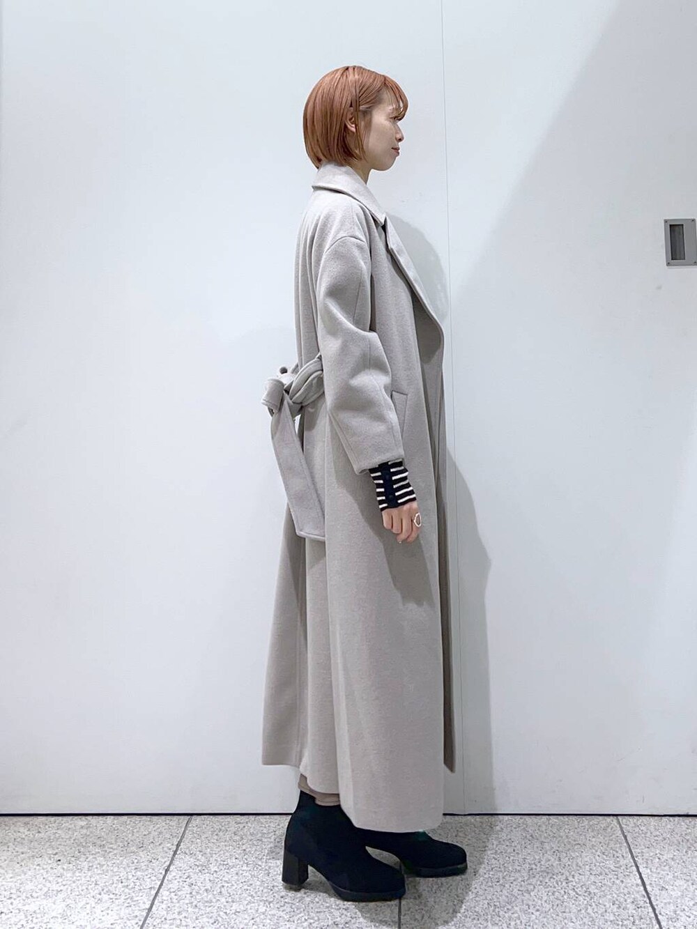 ブラック系のショルダーバッグ、ブラック系のブーツ、ブラウン系のスカートを着用したレディースの冬コーディネートの2枚目の写真