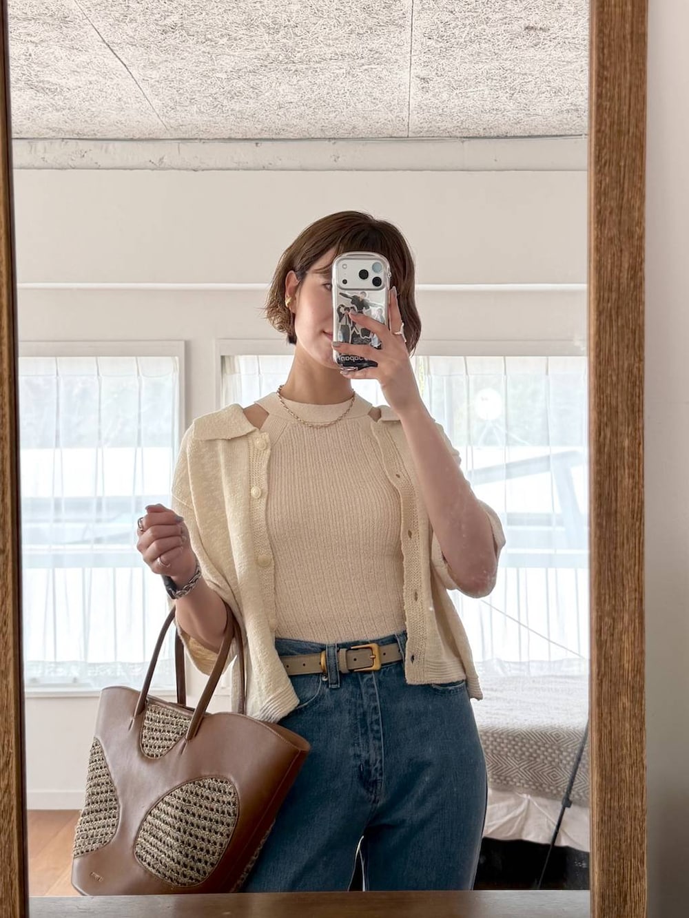 ブラウン系のトートバッグ、ブルー系のデニムパンツ、ブラック系のサンダルを着用したレディースの春コーディネートの9枚目の写真