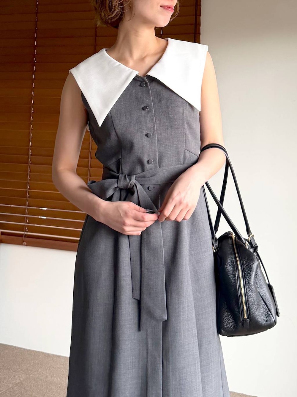 ブラック系のハンドバッグ、ブラック系のサンダル、グレー系のワンピースを着用したレディースの春コーディネートの4枚目の写真