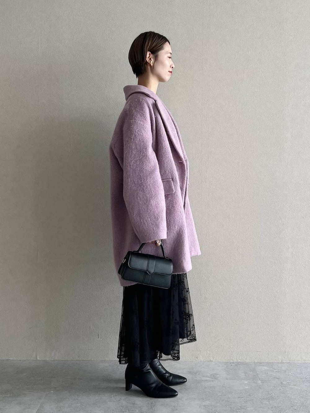 ブラック系のワンピース、パープル系のチェスターコート、ブラック系のブーツを着用したレディースの秋コーディネートの2枚目の写真