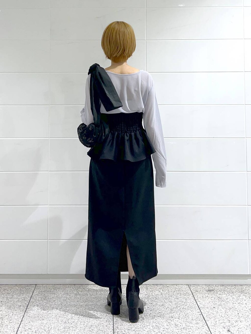 ブラック系のショルダーバッグ、ブラック系のスカート、グレー系のTシャツ/カットソーを着用したレディースの秋コーディネートの3枚目の写真