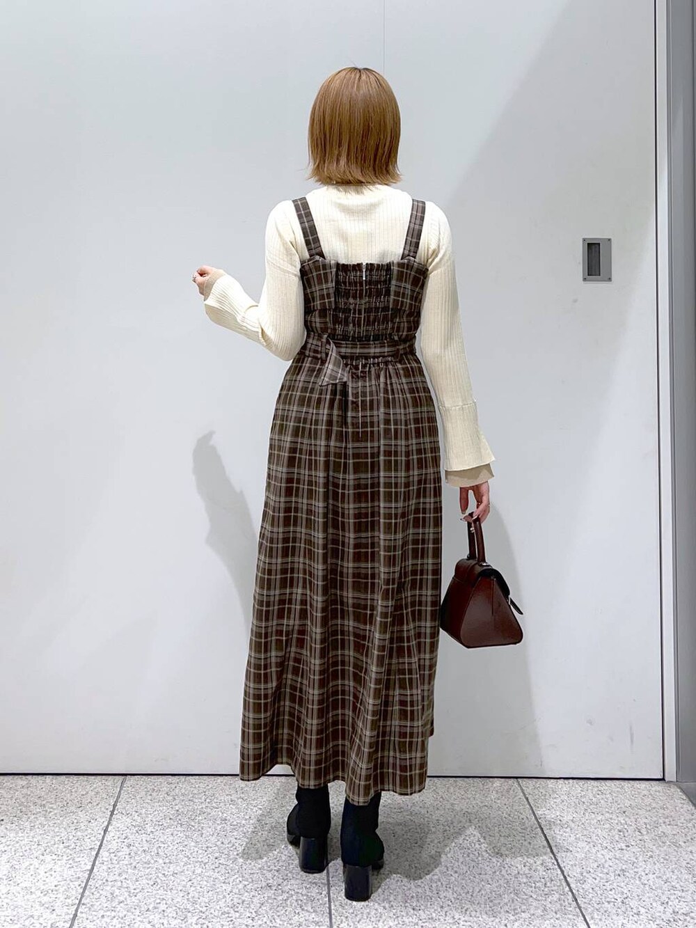 ブラック系のその他アウター、ブラウン系のハンドバッグ、ブラック系のブーツを着用したレディースの秋コーディネートの6枚目の写真